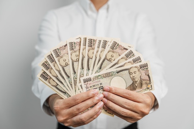 Man hand holding Japanese Yen banknote stack Thousand Yen money Japan cash Tax Recession Economy Inflation Investment finance and shopping payment concepts