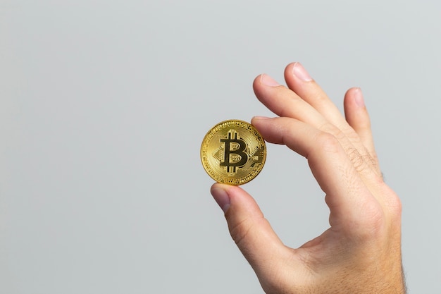 Man hand holding a physical bitcoin in front of a white background