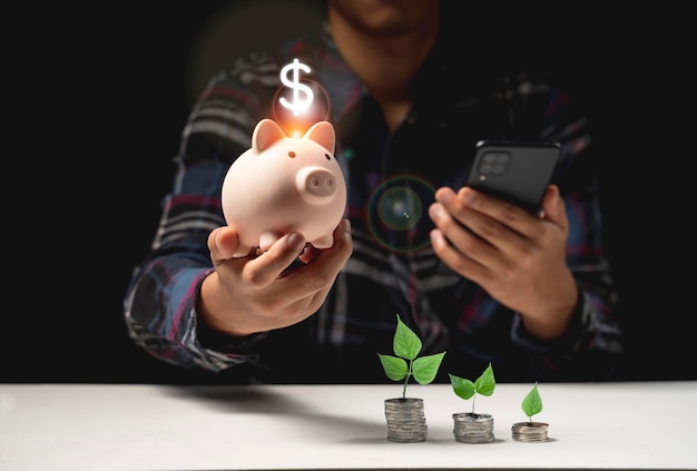 Man hand holding piggy bank and phone on table, saving money wealth and financial concept