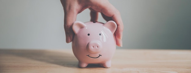 Man hand holding piggy bank on wood table Save money and financial investment