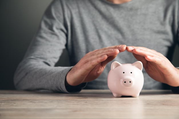 Man hand holding piggy bank on wood table Save money and financial investment