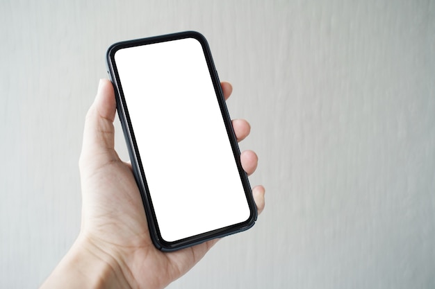 Man hand holding smartphone with blank screen on gray background.