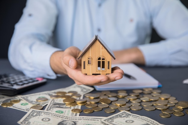 Man hand house model with money