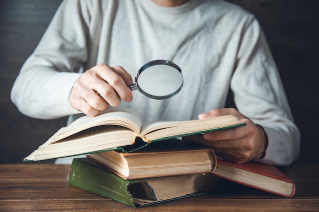 Man hand magnifier and books on the table