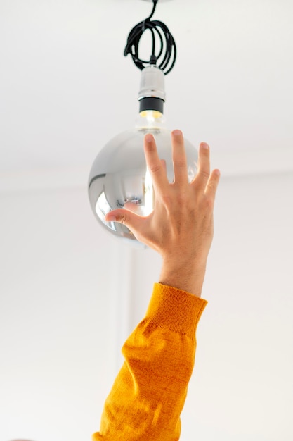 Man hand placing a giant modern light bulb with white wall