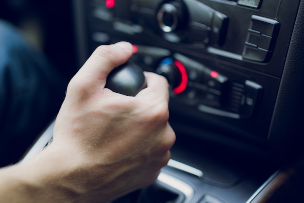 Man hand shifts gearbox in car salon. Close-up