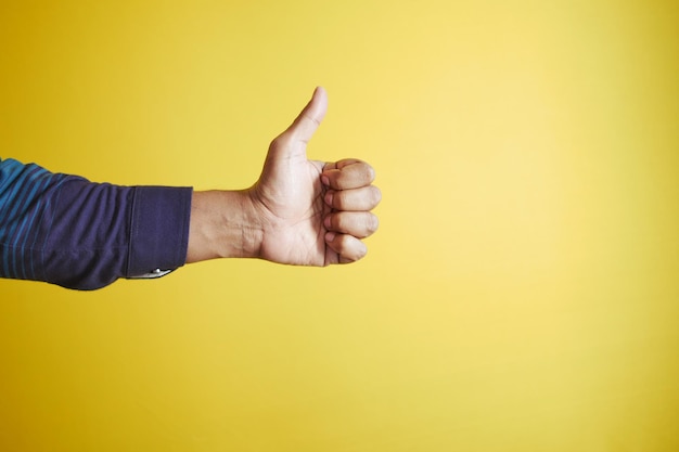 Man hand showing a thumbup on yellow background