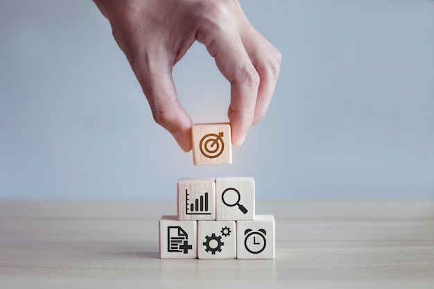 Man hand stack woods block step on table with icon business strategy and action plan