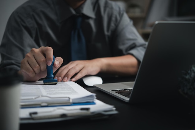 Man hand stamping approval signing on document or paperwork contract at desk