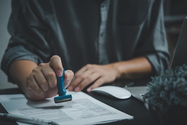 Man hand stamping approval signing on document or paperwork contract at desk