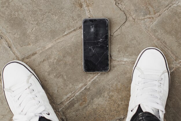 Man hand take broken damaged smartphone from asphalt