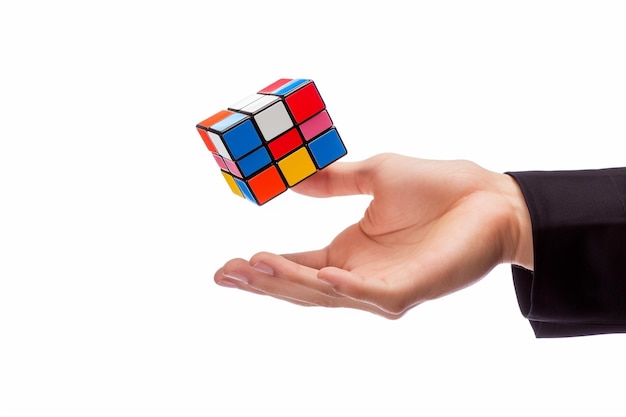 Man hand tossing a floating rubix cube on white background