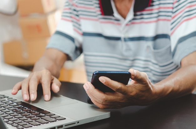 Photo man hand using smart phone and laptop on table at home, searching information browsing the internet on web, work from home.business shopping online concept