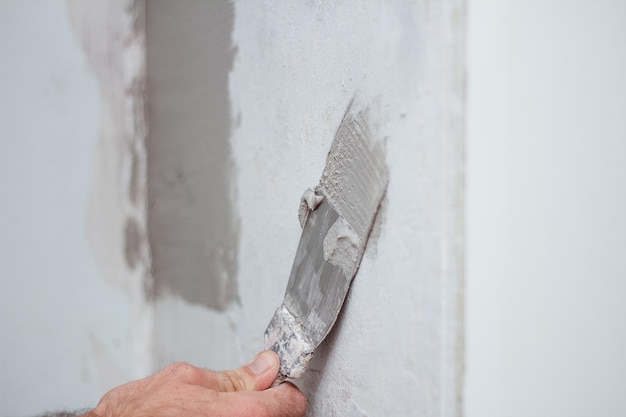 Man hand with trowel plastering a wall skim coating plaster walls