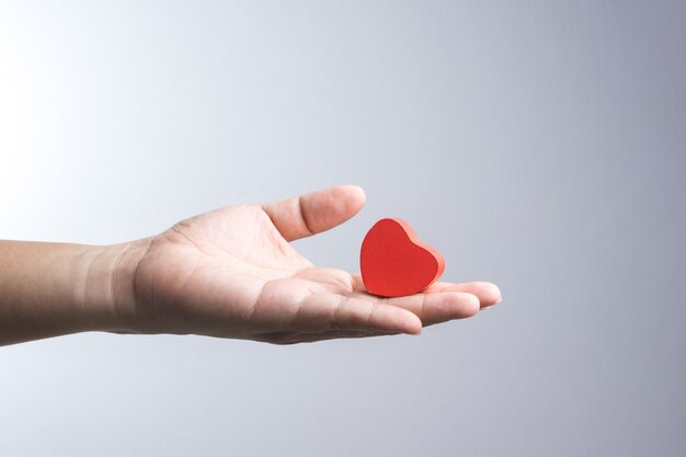 A man hand with wooden red heart object