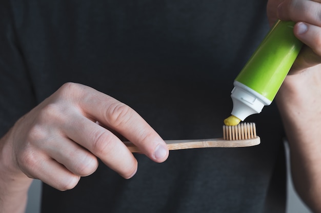 Man hands hold bamboo toothbrush with green toothpaste. Dental hygiene