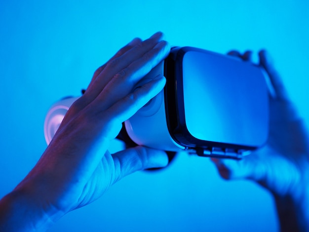 Man hands holding 3d 360 vr headset glasses in futuristic purple blue neon light.