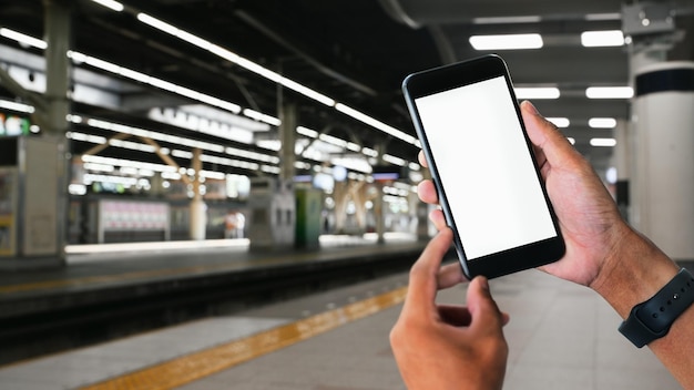 Man hands holding smartphone with railway station background