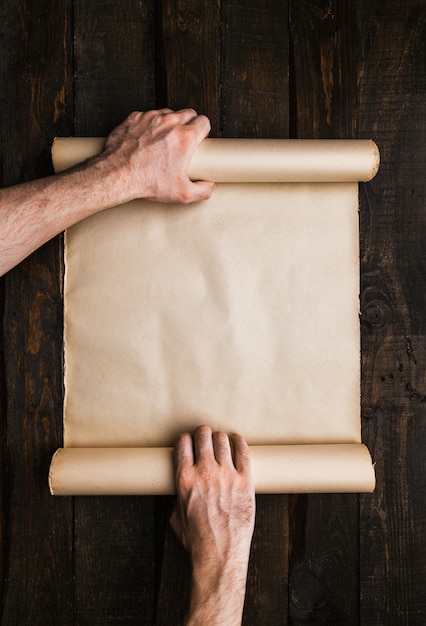 Man hands holding stressed paper roll on old barwood background. Wanderlust expedition creative concept. Empty space, room for text, lettering. Horizontal banner mockup.