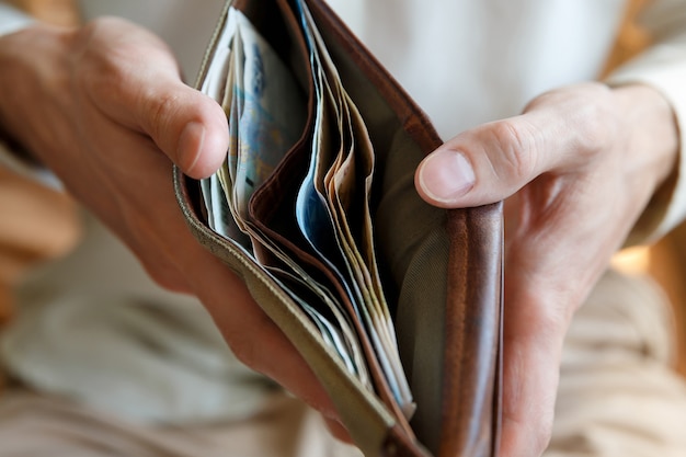 Man hands holding a wallet with money in it