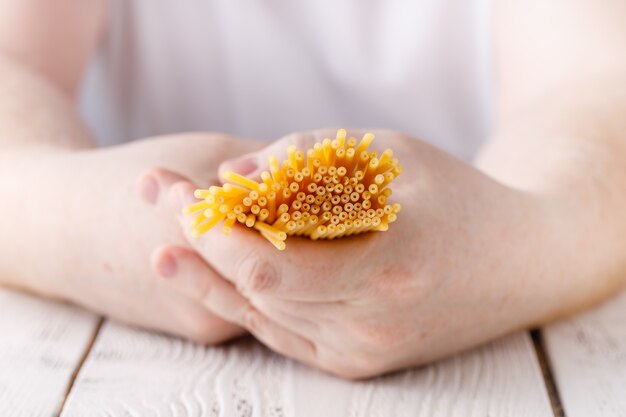 Man hands in the kitchen holding spaghetti