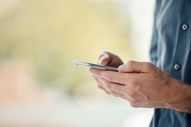 Man hands phone and mobile networking of a businessman in a office on web Online communication text writing and technology of a social media writer employee with mock up and blurred background