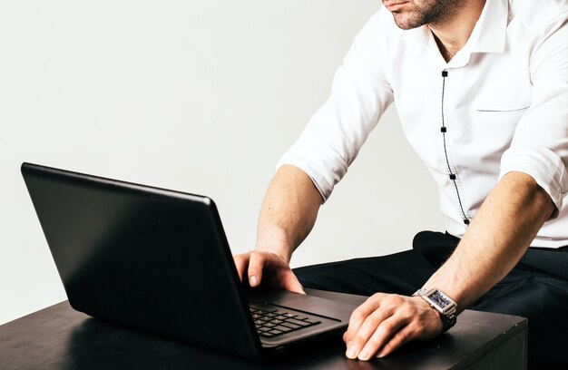 Man hands typing on laptop keyboard. Man in white shirt. Cropped photo. Close-up