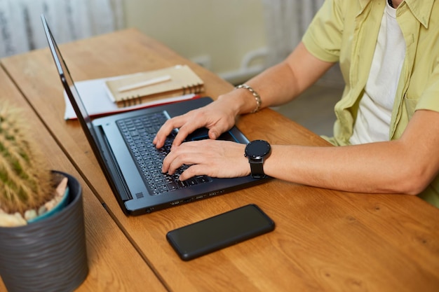 Man hands typing something on laptop working on computer at home