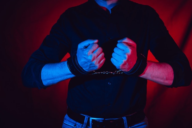 A man hands wearing a pair of black leather handcuffs