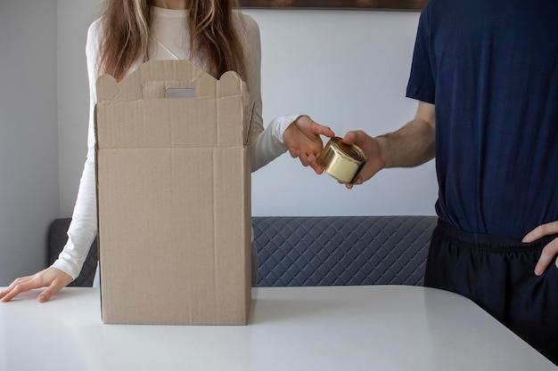 Man hands a woman a packed canned meal to put in a charity box