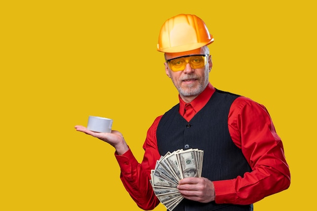 A man in a hard hat holding a cup and money