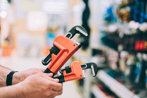 A man in a hardware store holds an adjustable wrench.