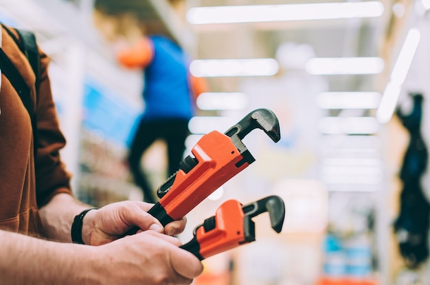 A man in a hardware store holds an adjustable wrench.