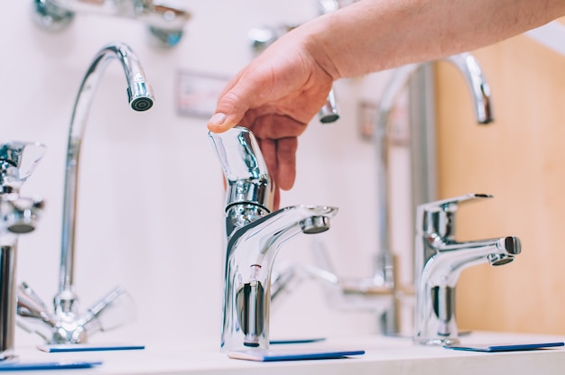 A man in a hardware store selects a faucet for the sink and washbasin.