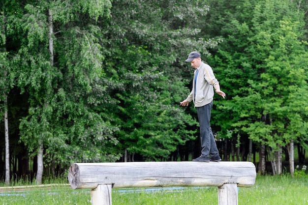 A man has fun in the park and walks on a log checking his balance