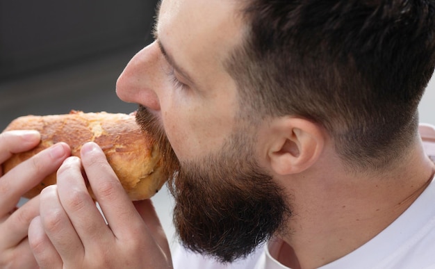 Man has lunch. He is looking at his sandwich and to eat it immediately.