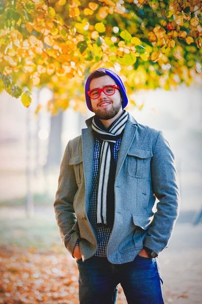 Man in hat and glasses on autumn season alley