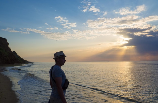 Man in hat going on the waves of the sea at sunrise