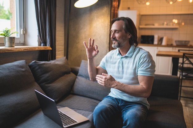 A man having a video call and using fingers language