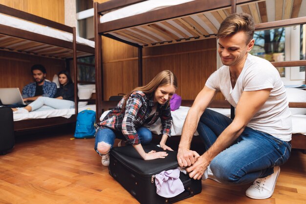 Photo man helps girl stack things and close valise.