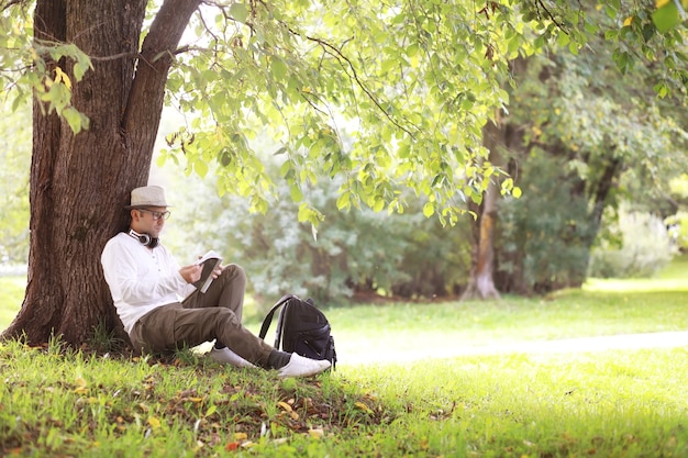 A man hides in the shade of trees on a hot day. Lunch break. Rest in the middle of the working day.