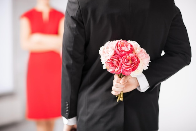 man hiding bouquet of flowers behind his back.