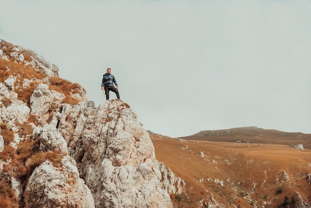 Man hiker standing on the top mountain cliff peak Adventure extreme sport outdoor