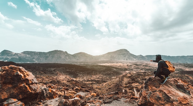 Man hiker on the top of the mountain pointing at the sunset panorama view. Successful, motivational and inspirational concept