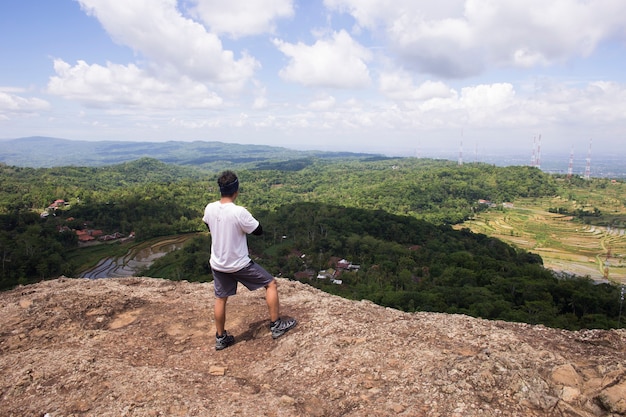 Man hiker with a backpack on top of the mountain back