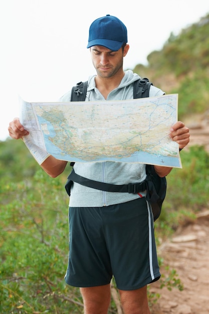 Man hiking and map for direction nature and guide on trail fitness and exercise on holiday Male person lost and documents for information travel and journey or adventure to forest for cardio