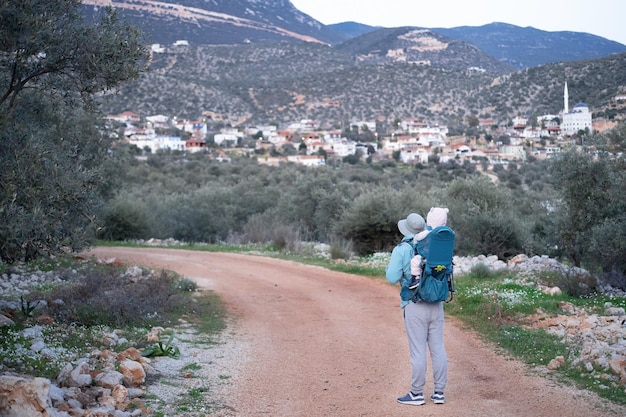 Man hiking in mountainscarrying baby in bacpackslingcarrierfamily travellingtripslifestylefatherchil