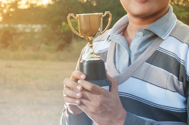 Man hold gold trophy cup