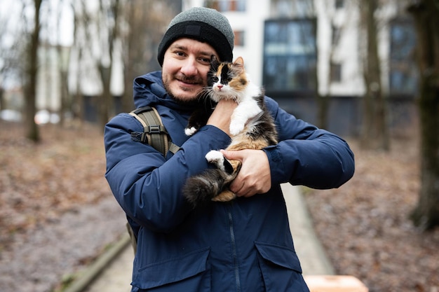 Man hold kitten in hands outdoor at park