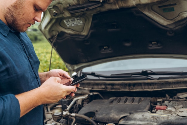 Man hold phone in hand opened hood on background